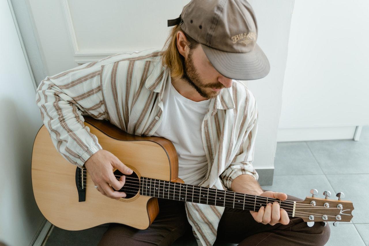 Chico sentado en el piso tocando la guitarra.