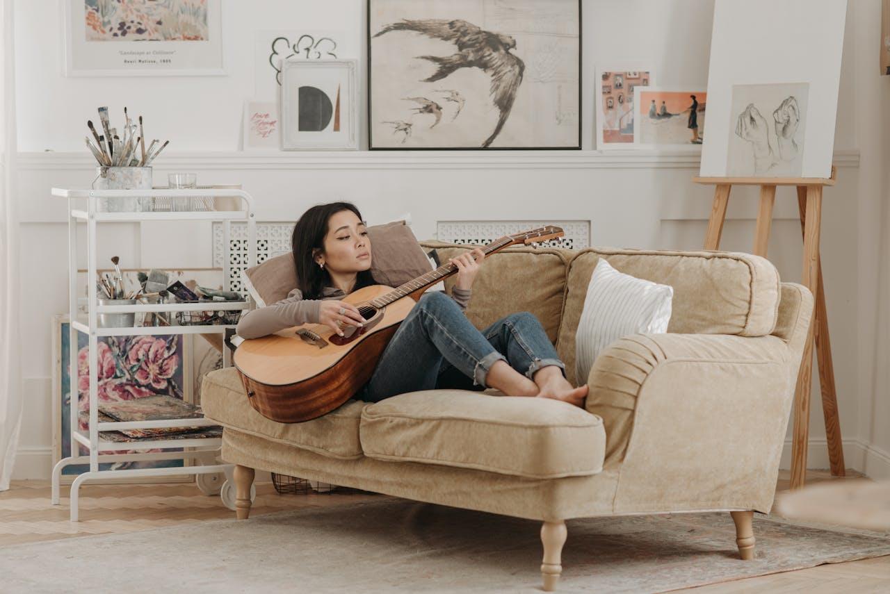 Mujer con guitarra recostada en el sillón. 