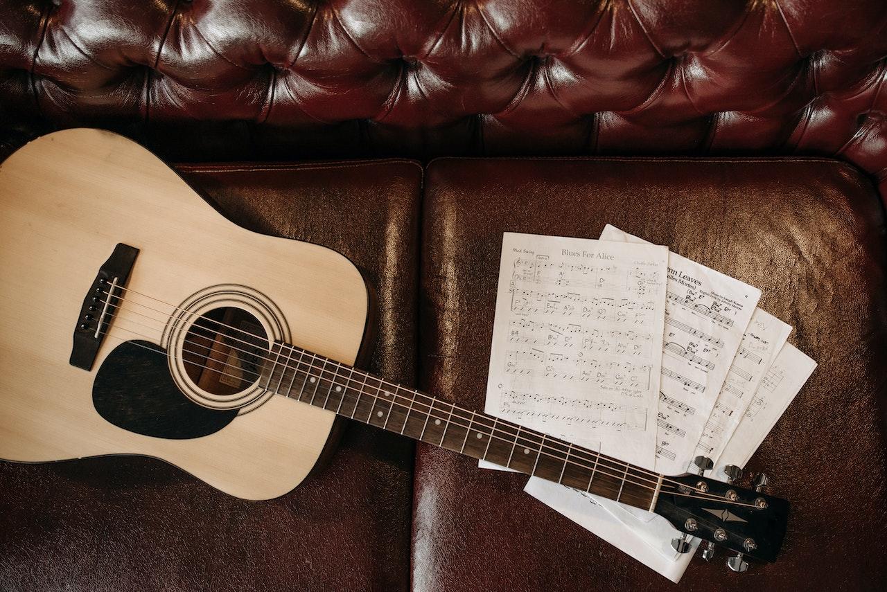 Guitarra y partituras sobre el sillón.