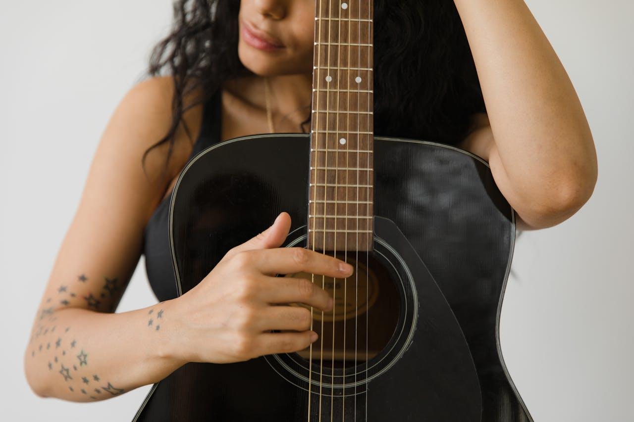 Mujer abrazando guitarra negra.