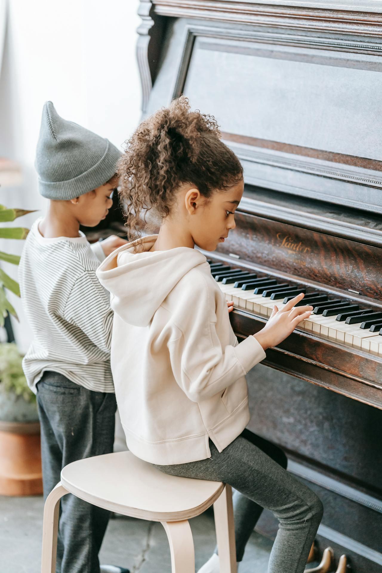 Niño y niña tocando piano de madera.