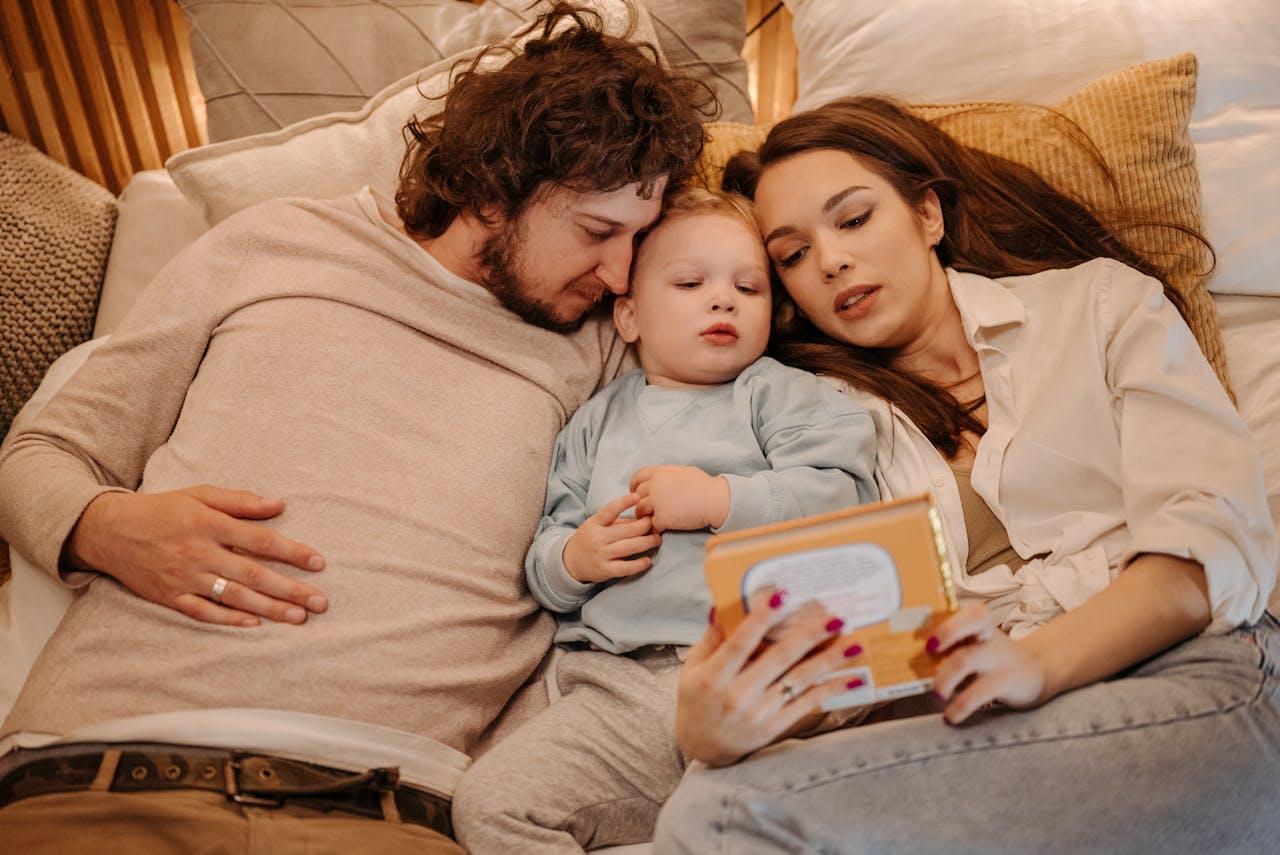 Madre, padre y bebe leyendo en la cama.