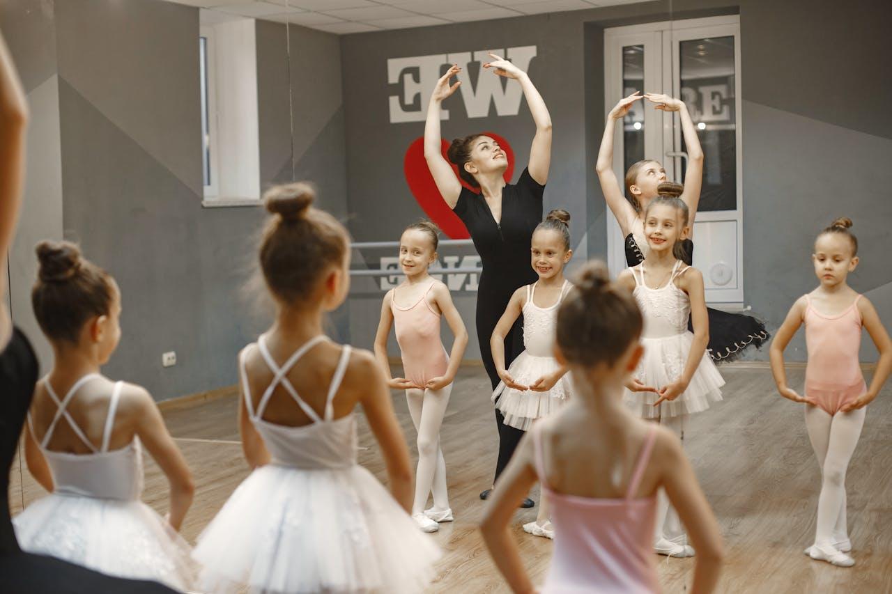 Niñas vestidas de blanco y adulta bailando frente al espejo.