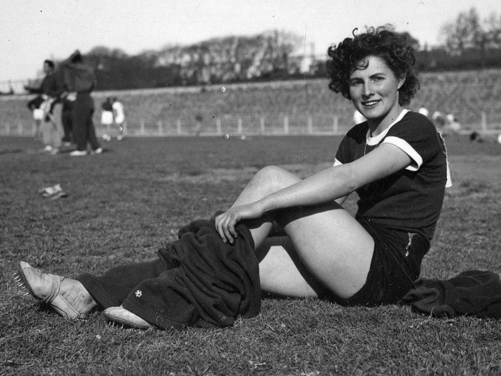 Mujer sentada en el pasto poniéndose en pantalón.