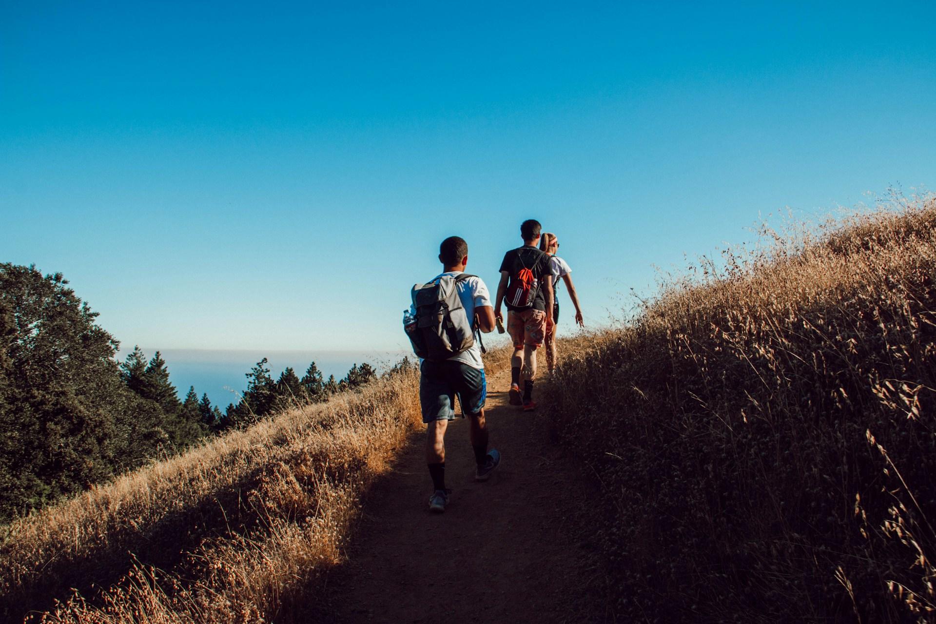 Tres personas caminando en la montaña.