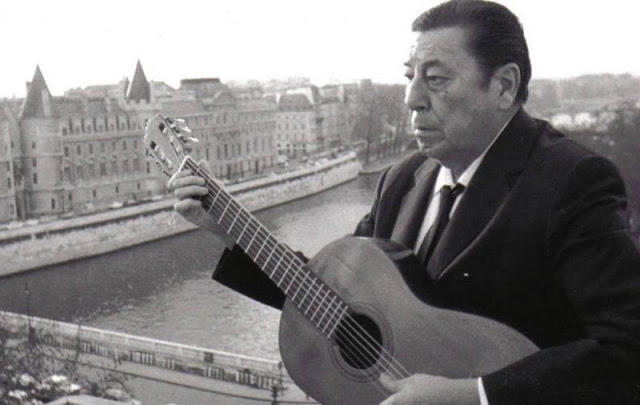 Hombre con traje negro con una guitarra.