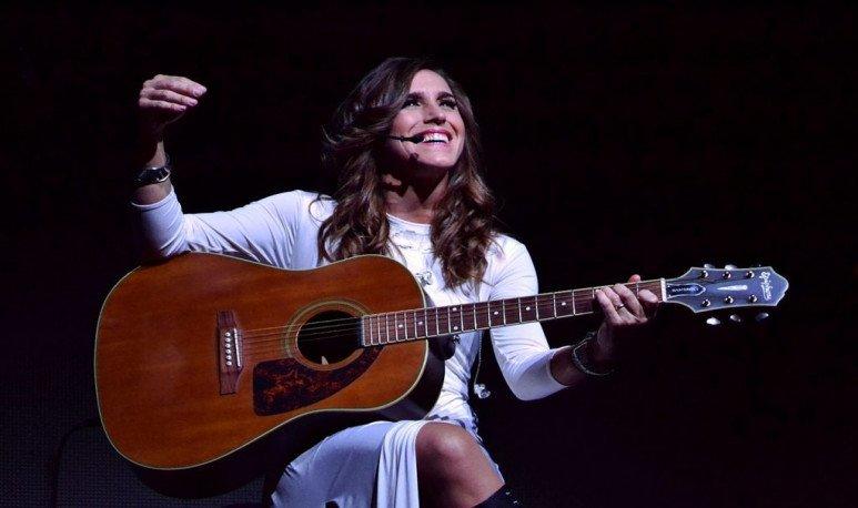 Mujer sentada con vestido blanco y guitarra.