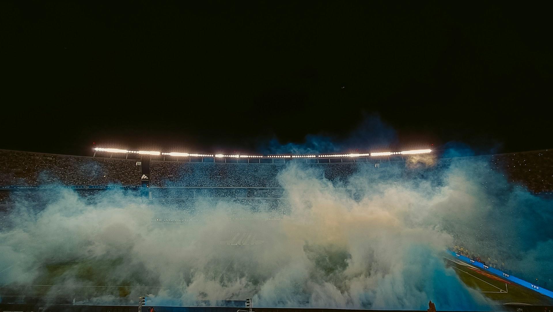 Estadio con humo blanco y celeste.