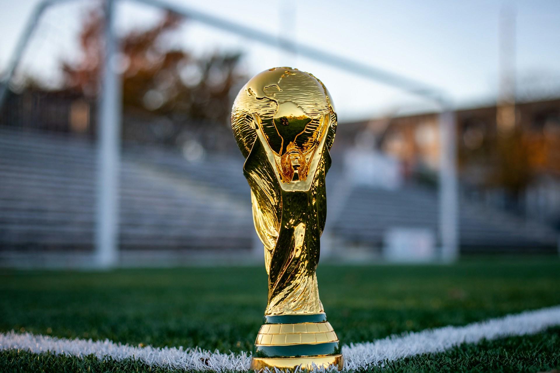 Copa dorada sobre césped verde y blanco.