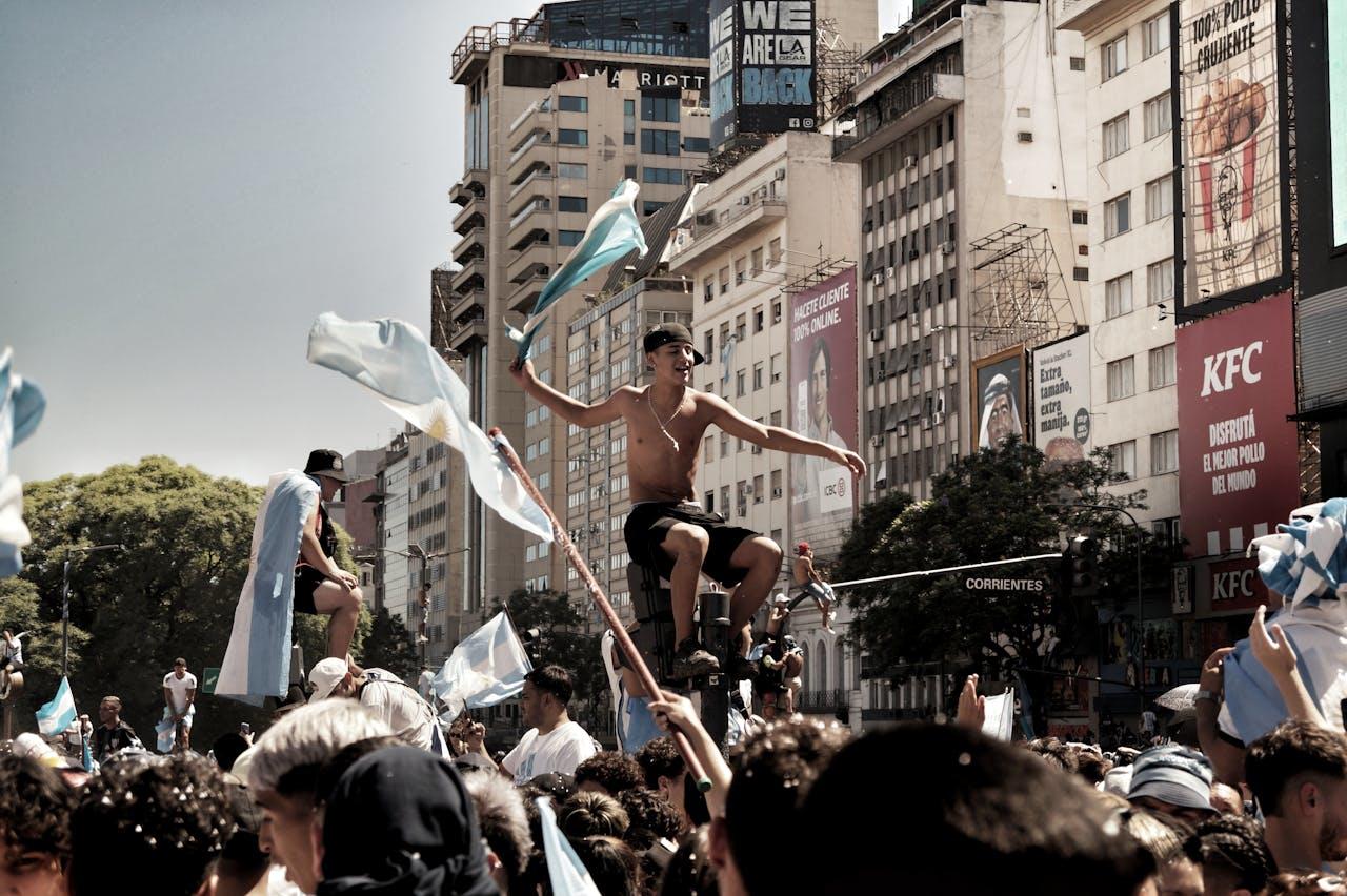 Muchedumbre festejando en la calle con banderas.