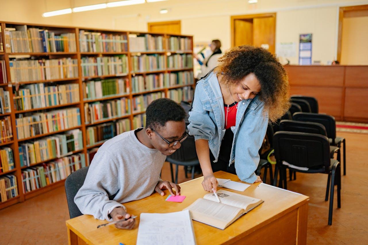 Dos jóvenes leyendo en el escritorio de la biblioteca.