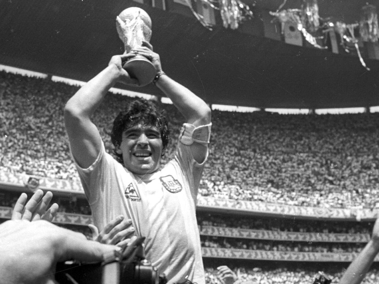 Foto en blanco y negro de un hombre con un trofeo delante de la multitud.