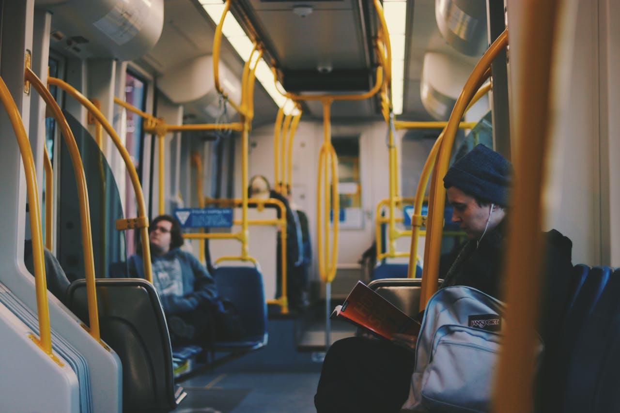 Hombre leyendo en el metro con auriculares.