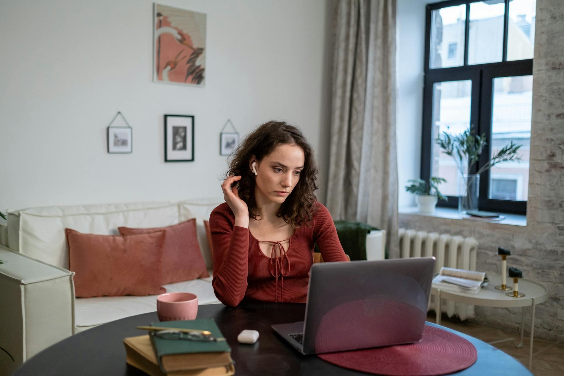 Mujer sentada en la mesa frente a la computadora portátil.