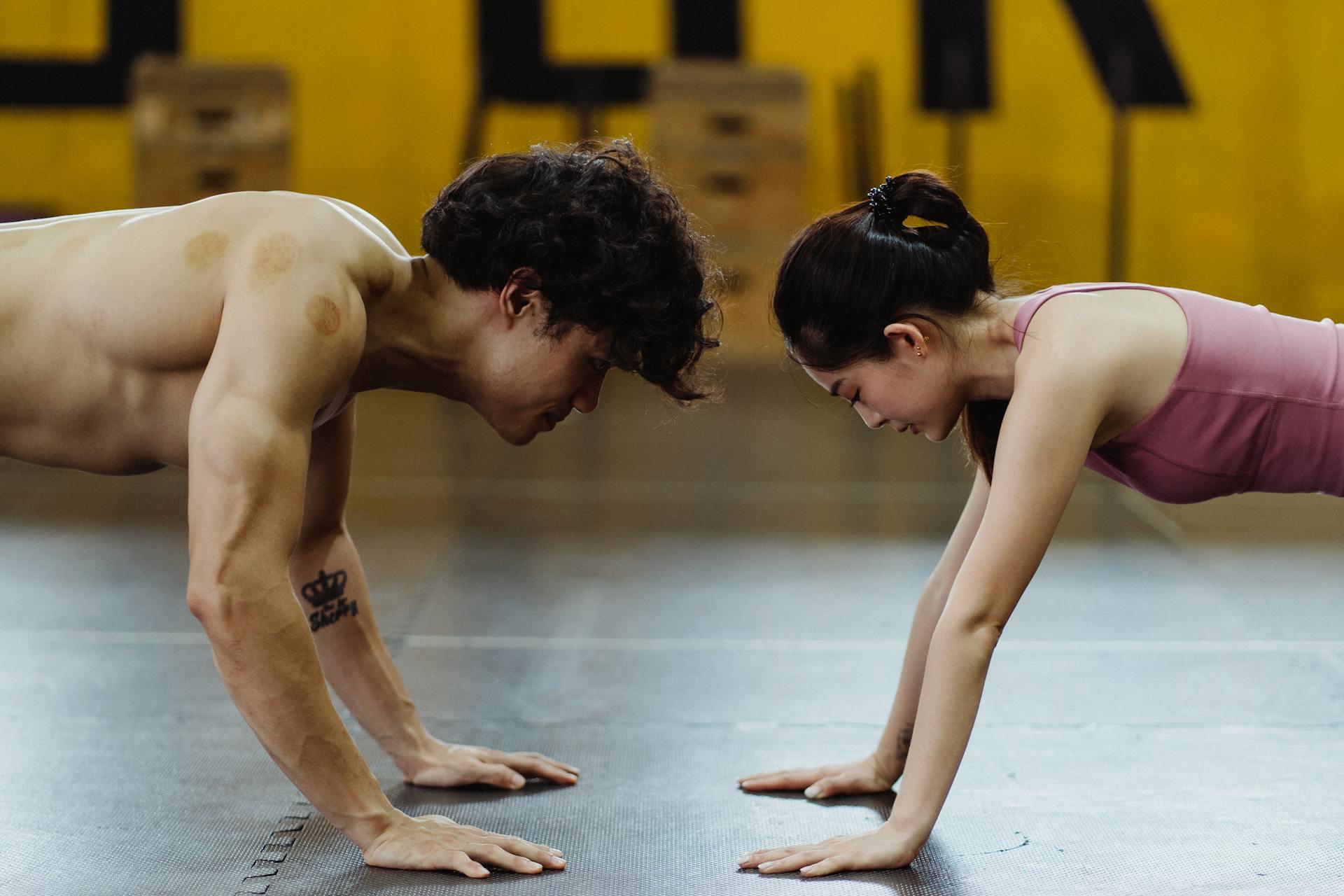 Hombre y mujer enfrentados haciendo la plancha.