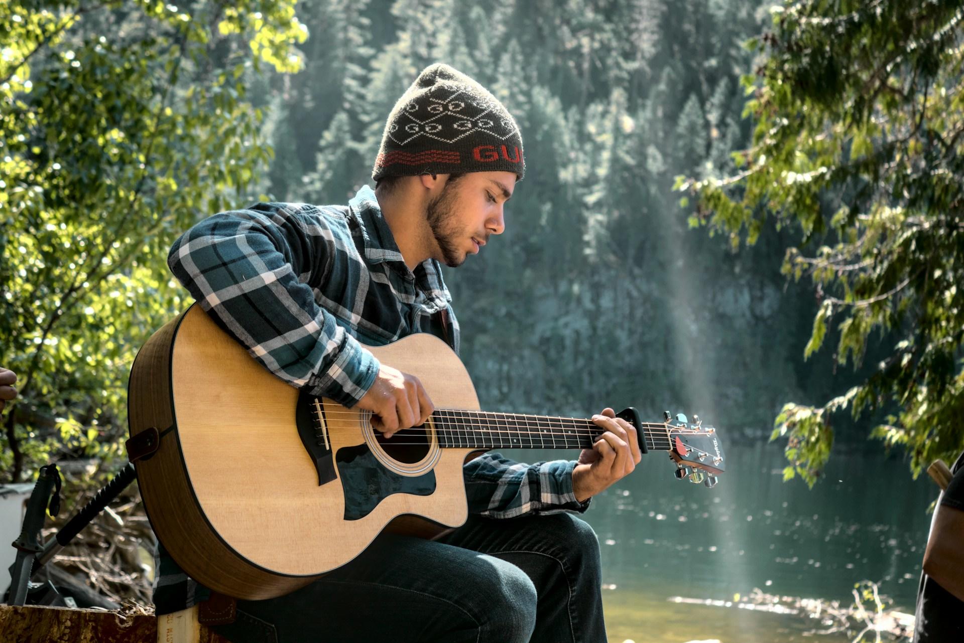 Hombre tocando la guitarra sobre el lago.