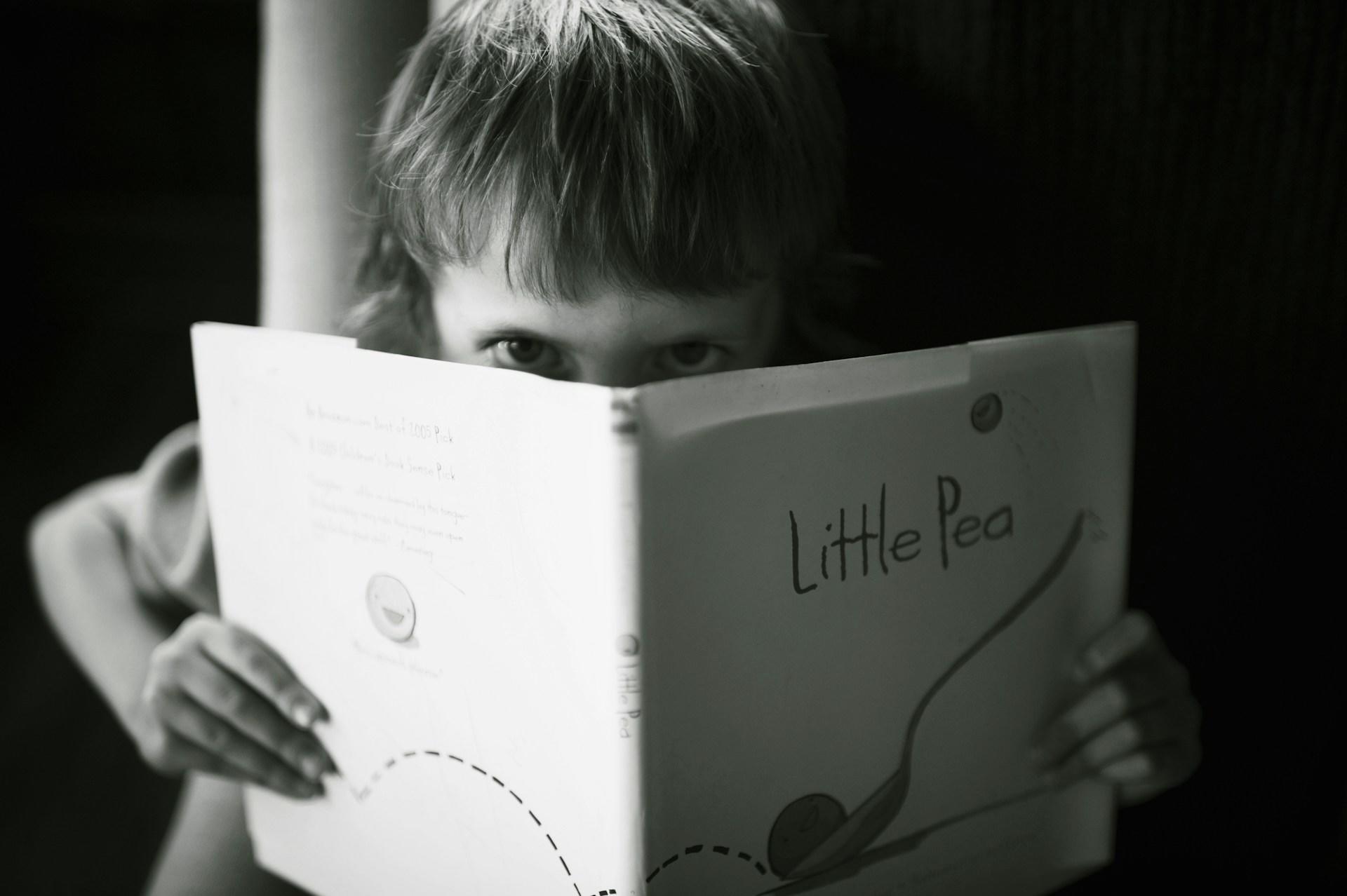Niño sosteniendo un libro en blanco y negro.