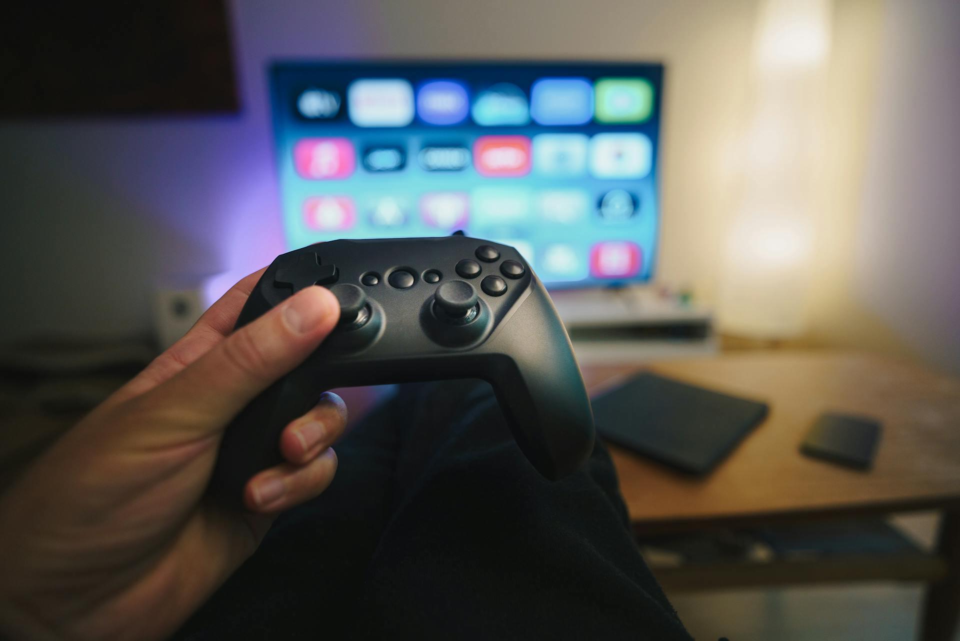 Control de videojuego frente a la pantalla de TV encendida.