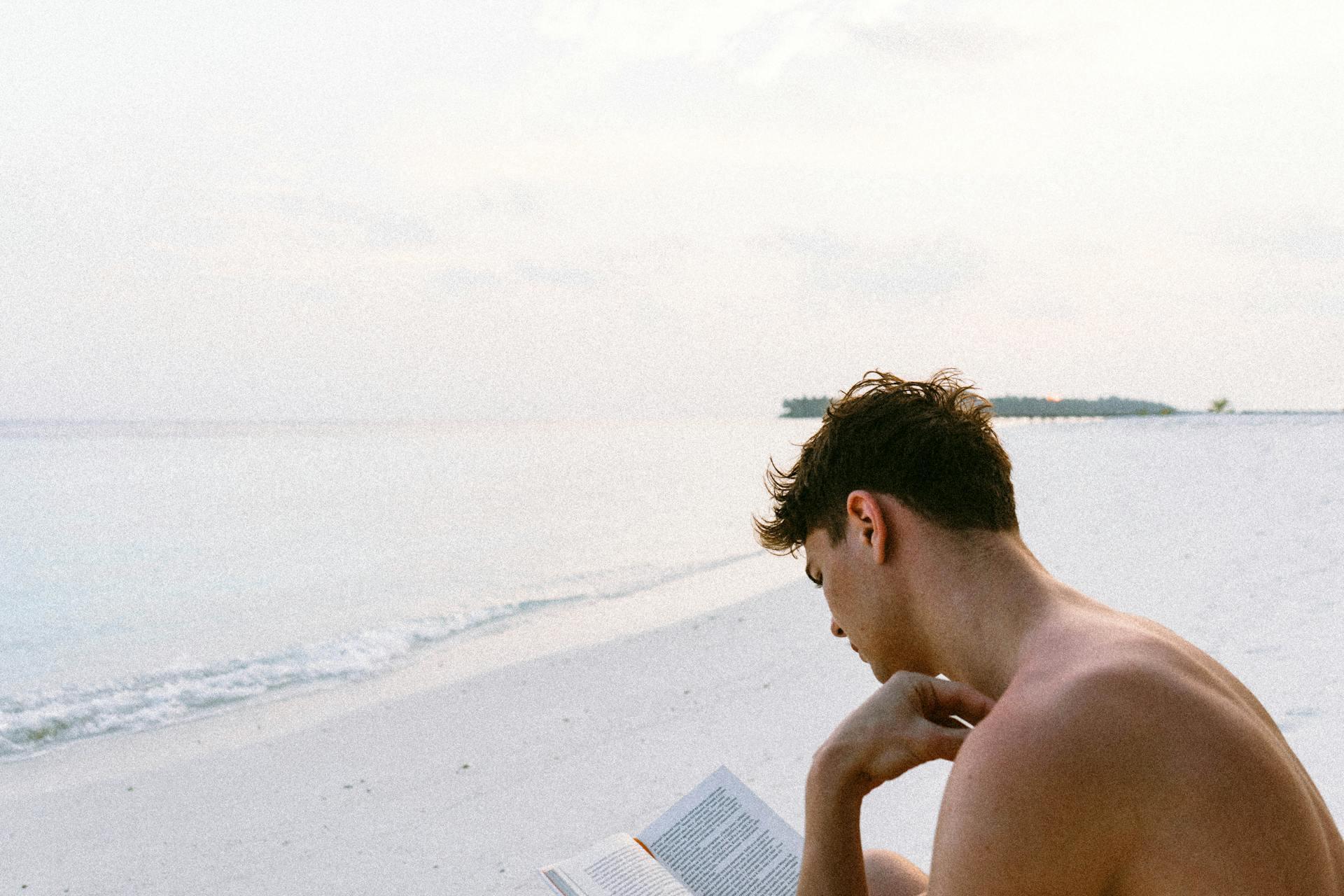 Hombre leyendo en la orilla del mar.