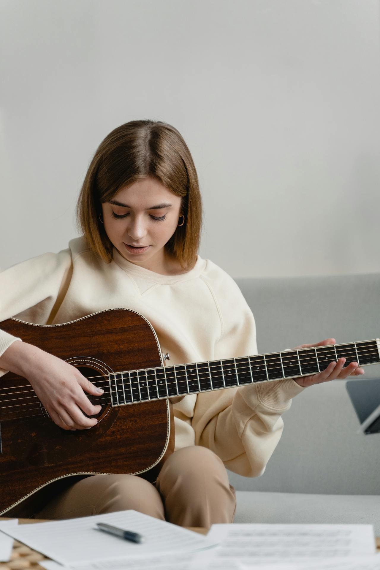 Mujer sentada en el sillón sosteniendo una guitarra.