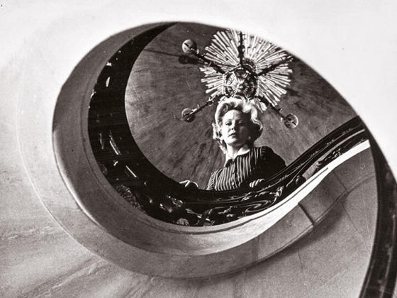 Fotografía en blanco y negro de una mujer mirando desde arriba de la escalera.