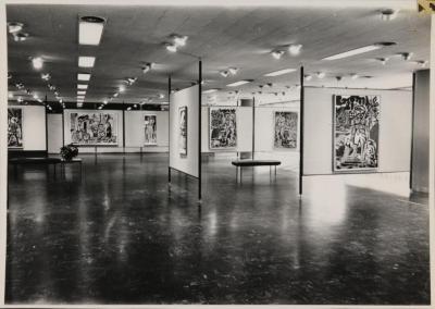 Foto en blanco y negro de una sala con cuadros colgando de las paredes.