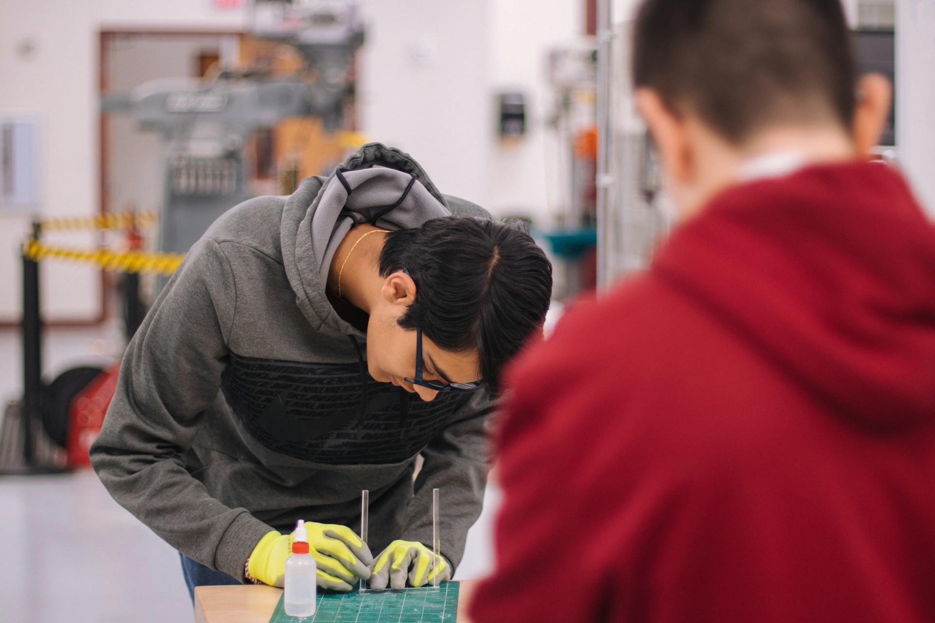 Hombre con buzo gris y guantes amarillos trabajando sobre un trabajo.