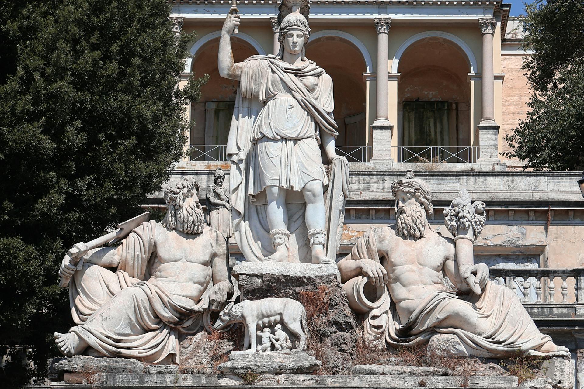 Tres estatuas de piedra blanca con figuras antiguas.