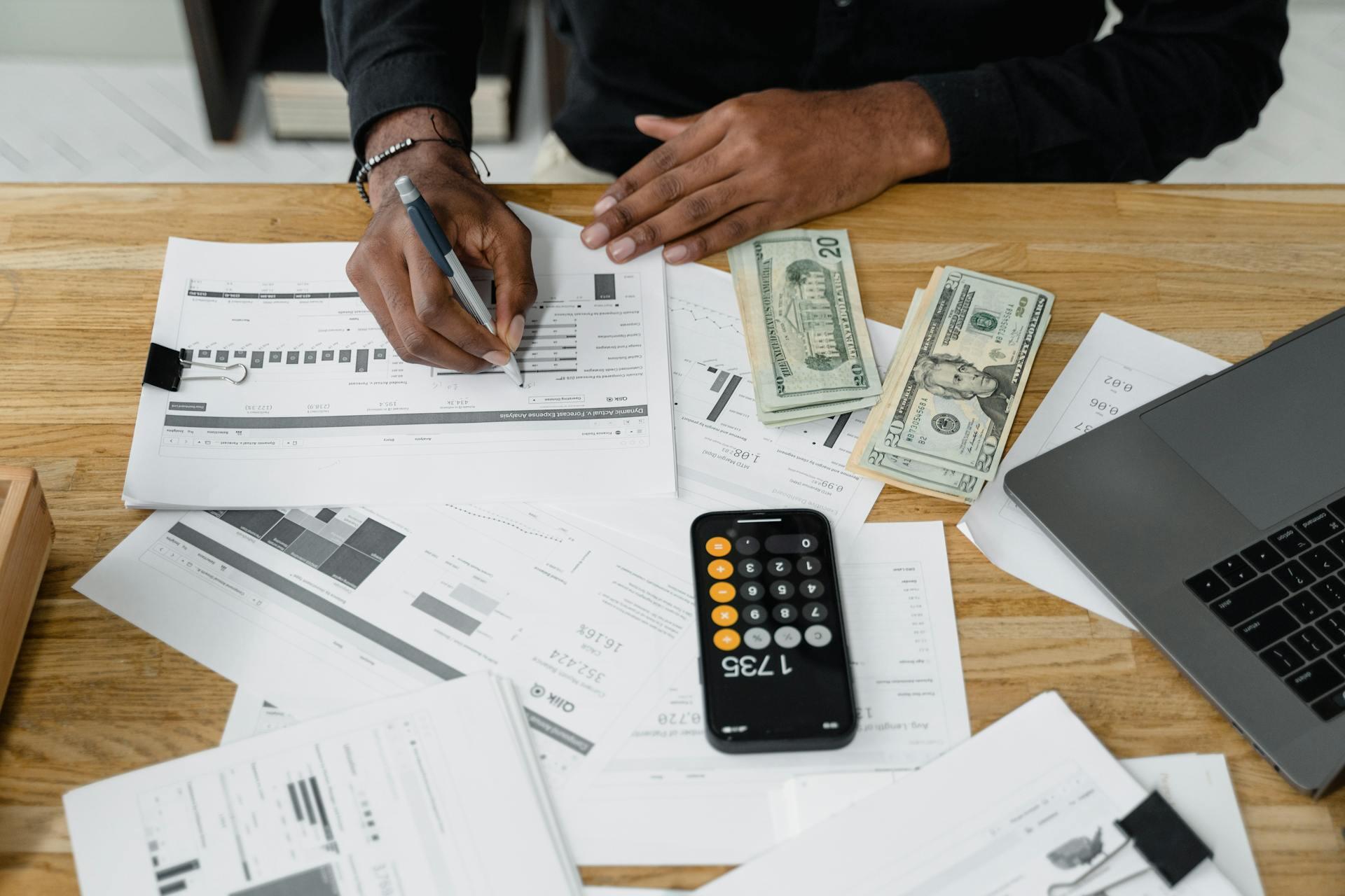 Calculadora, billetes y papeles sobre la mesa de madera.
