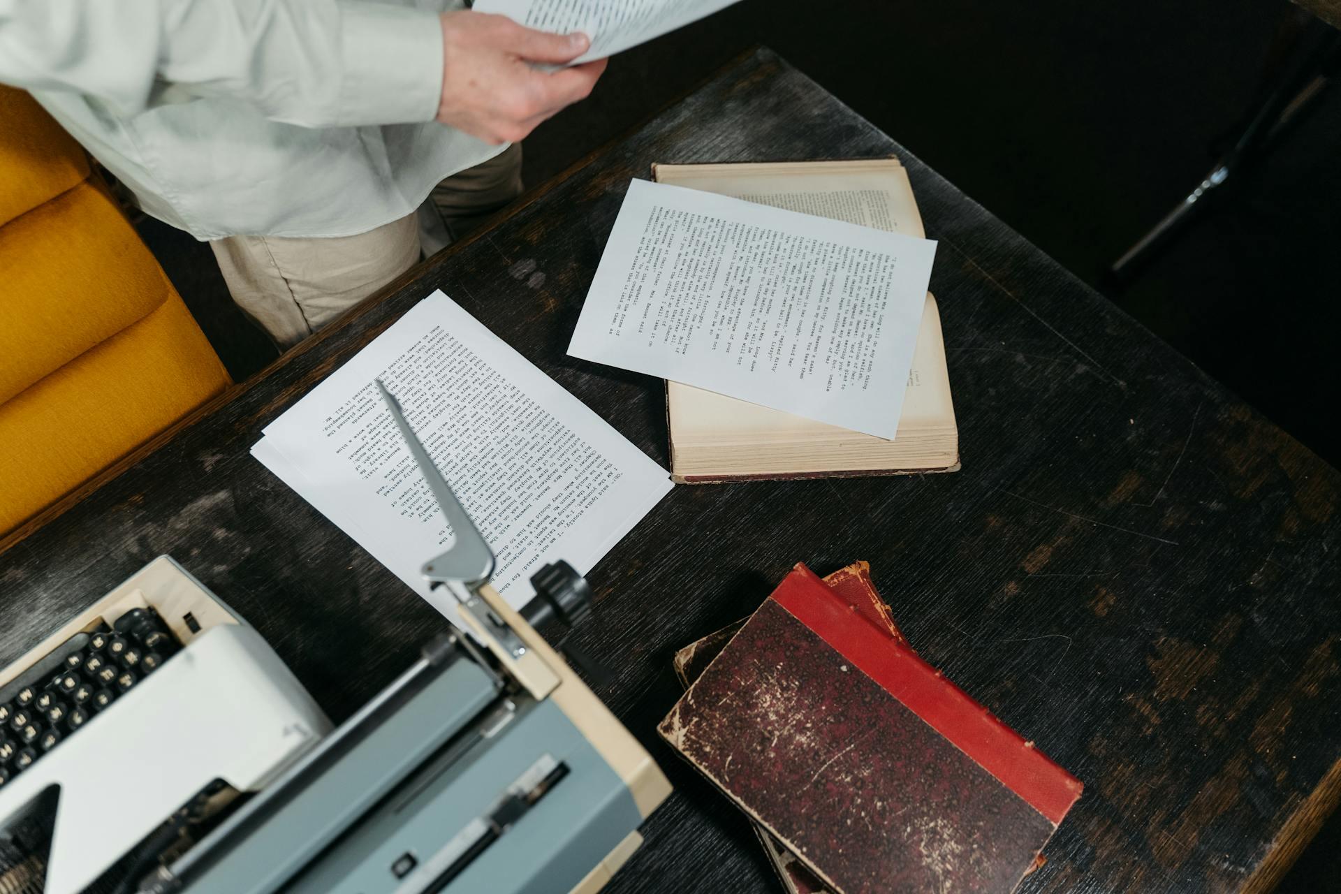 Papeles, libros y máquina de escribir sobre la mesa de madera.