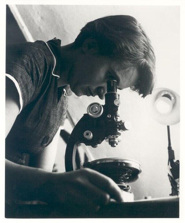 Mujer mirando por un microscopio.