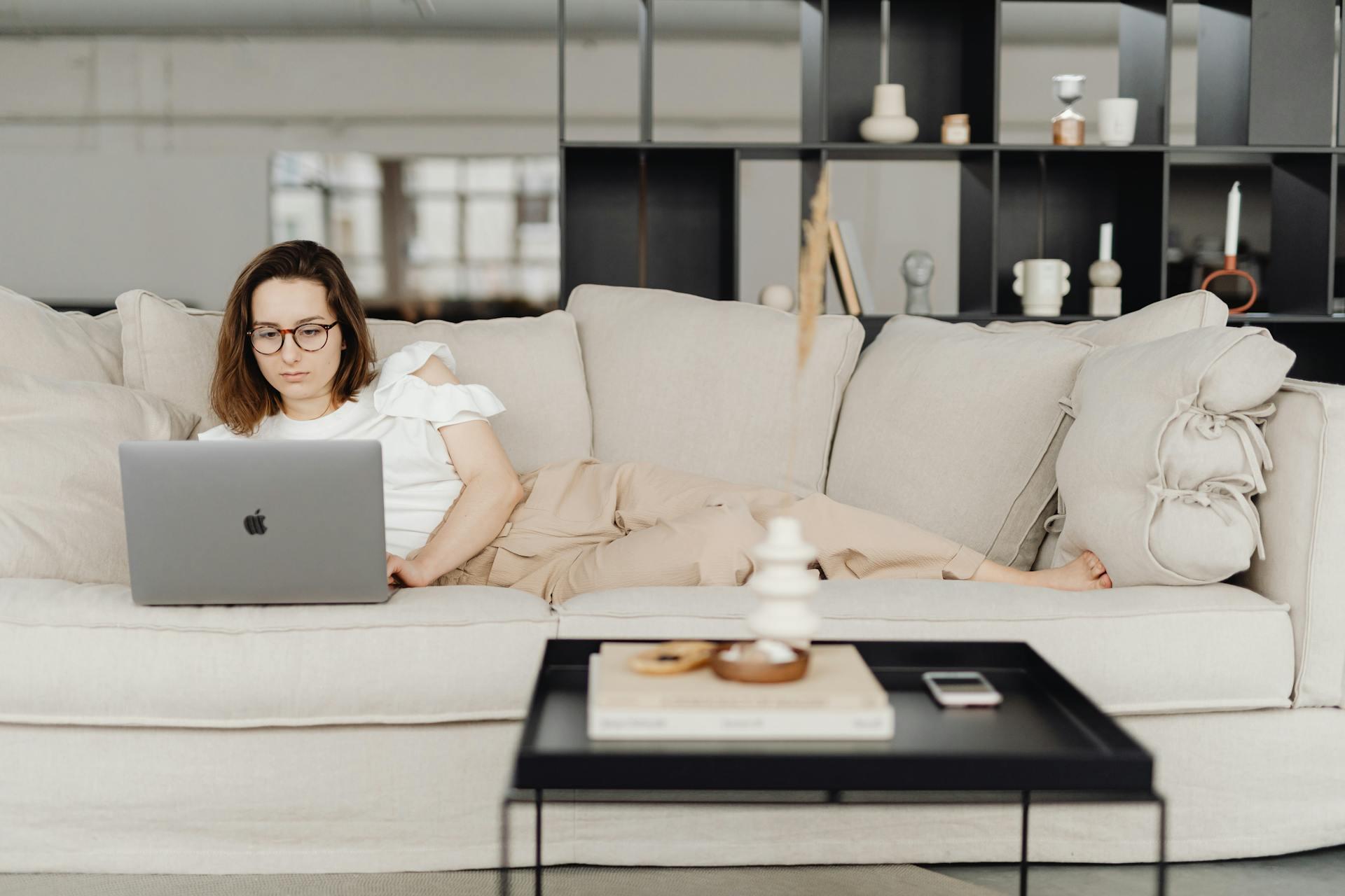Mujer acostada en el sillon con la pc.