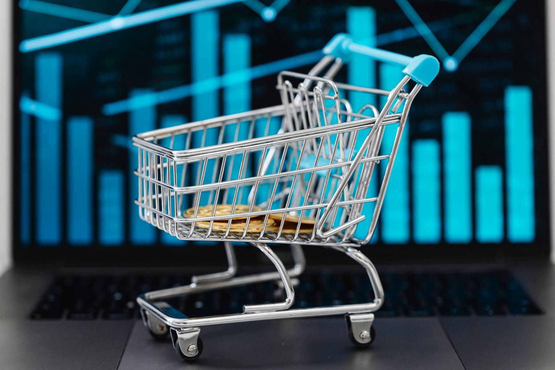 Carrito de supermercado con monedas delante de un gráfico de barras.