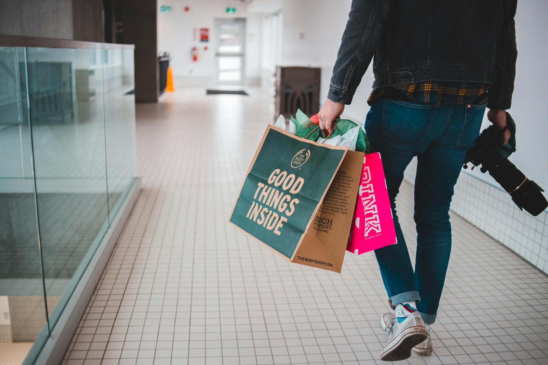 Hombre caminando con bolsas de compras en la mano.