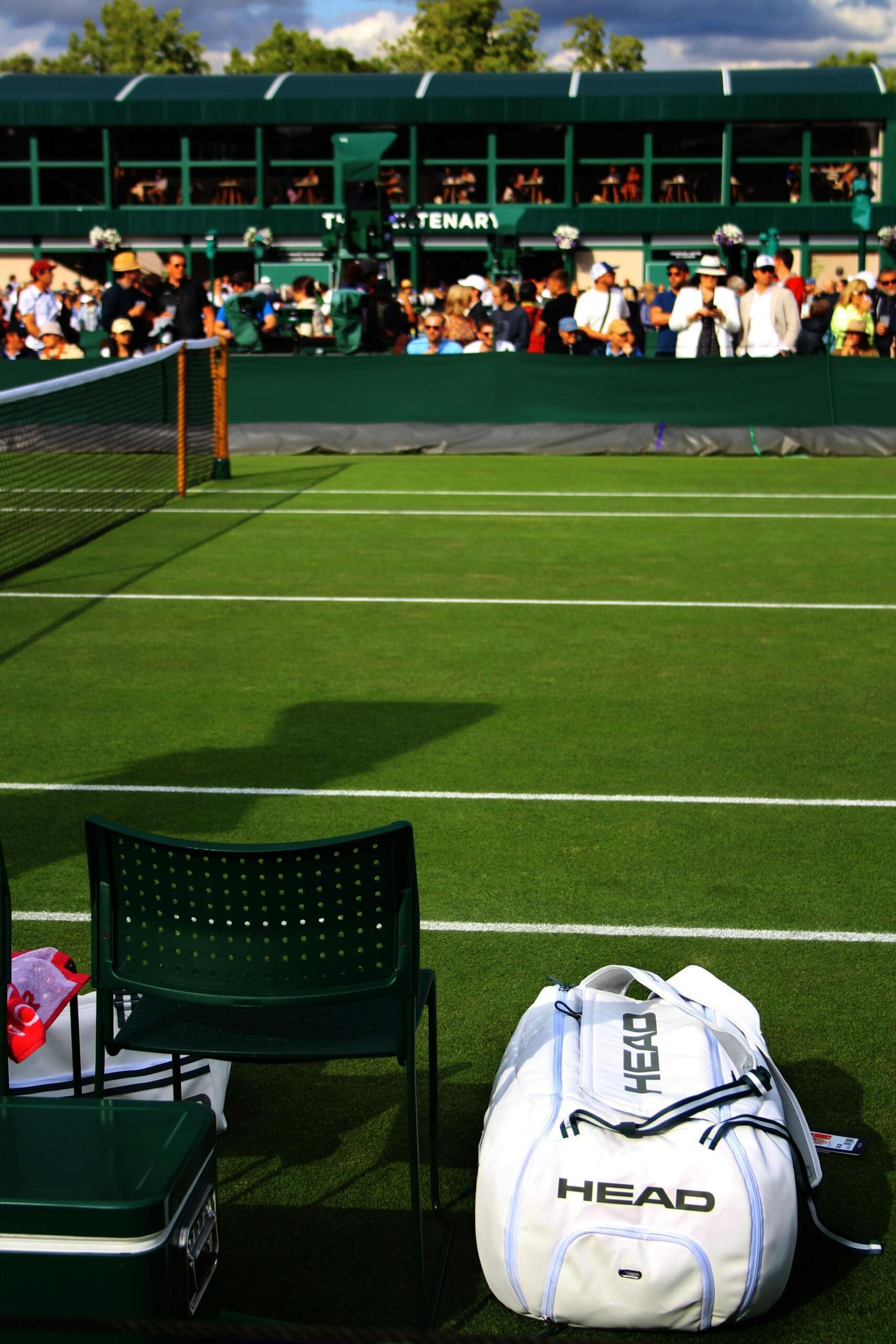 Silla y bolso al costado de la cancha de tenis.