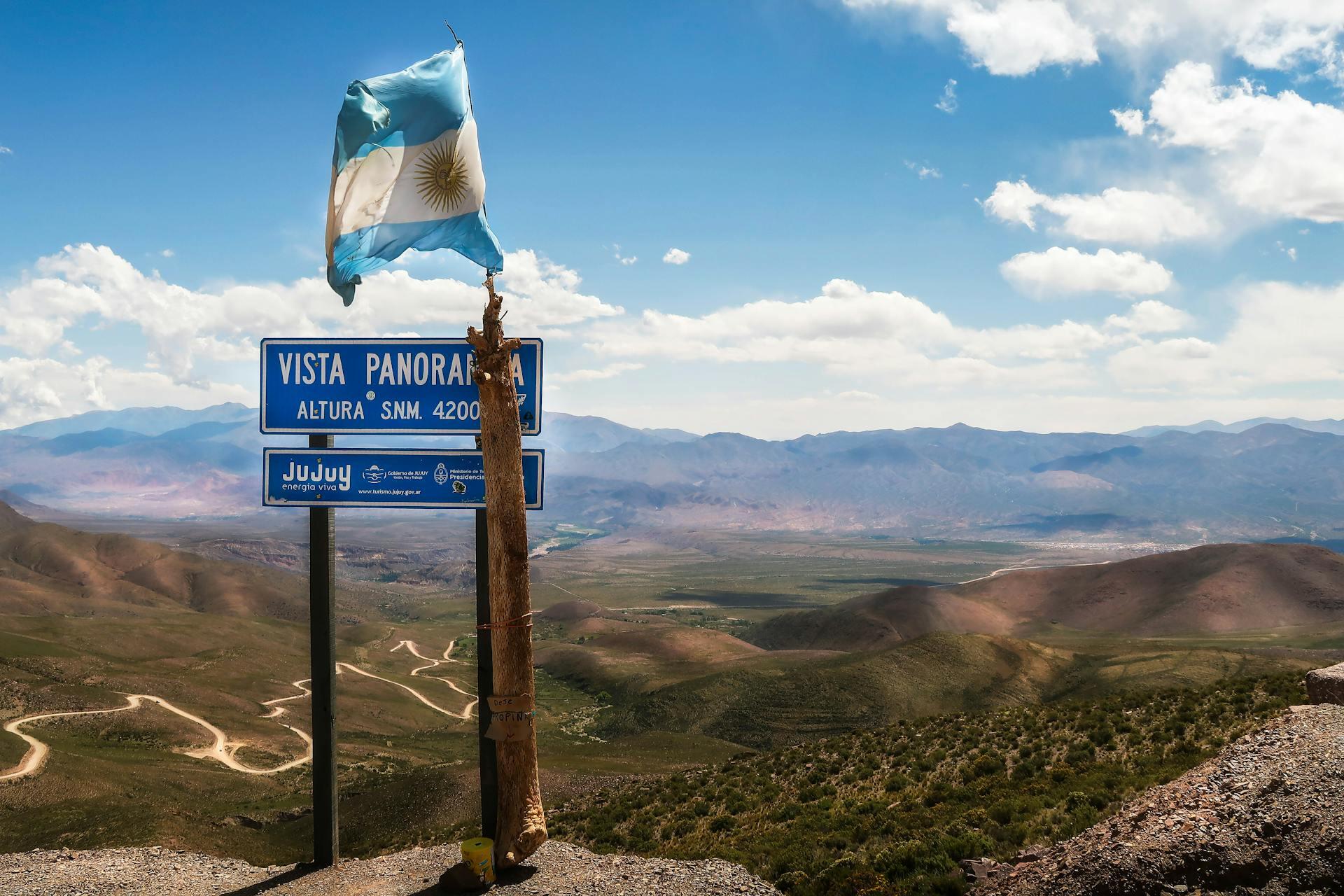 Bandera blanca y celeste Flameando frente al cartel azul. 