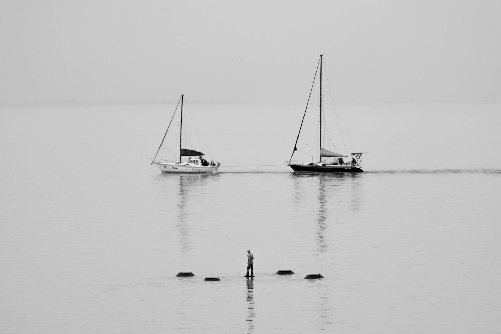 Hombre y barcos en el río nublado.