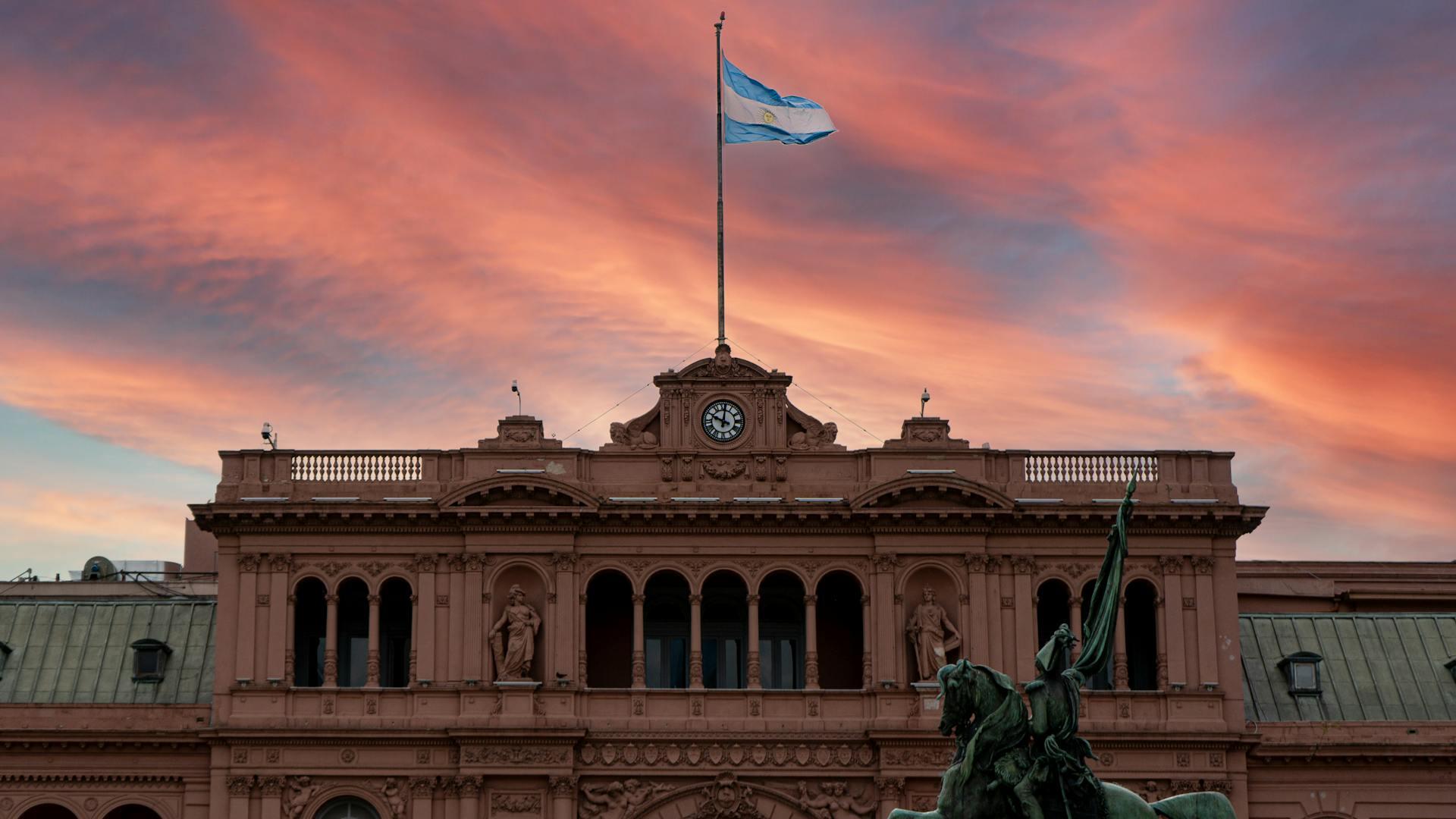 Casa rosada con bandera blanca y celeste de Argentina. 