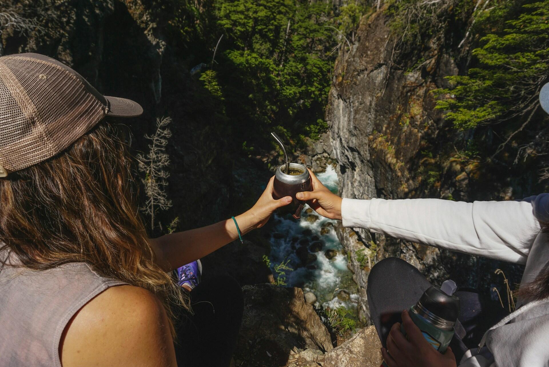 Dos personas delante del paisaje tomando un mate. 