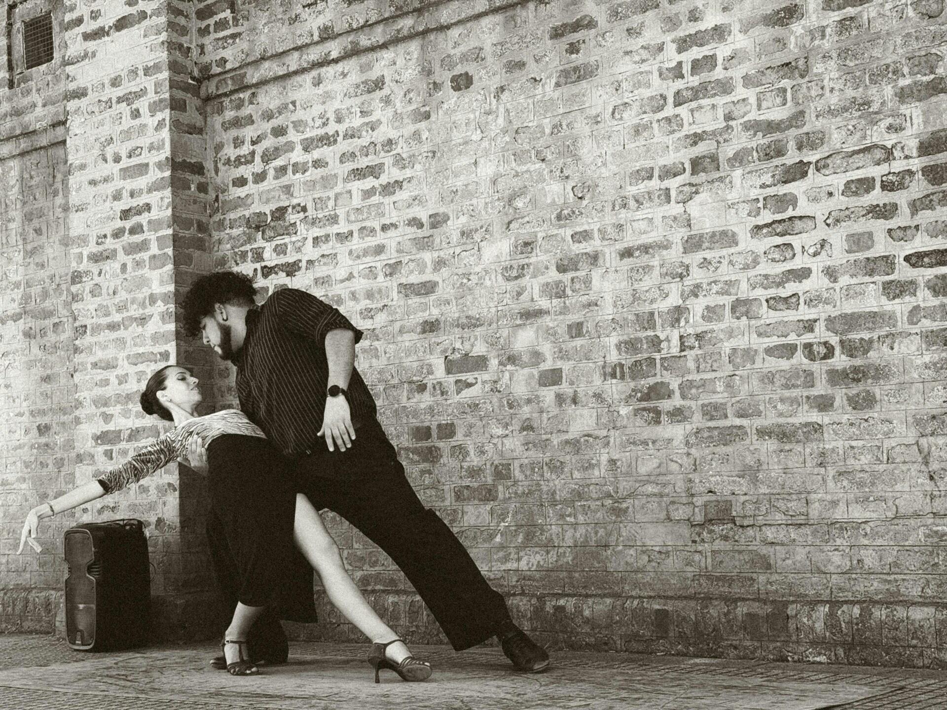 Pareja bailando delante de la pared de ladrillos.