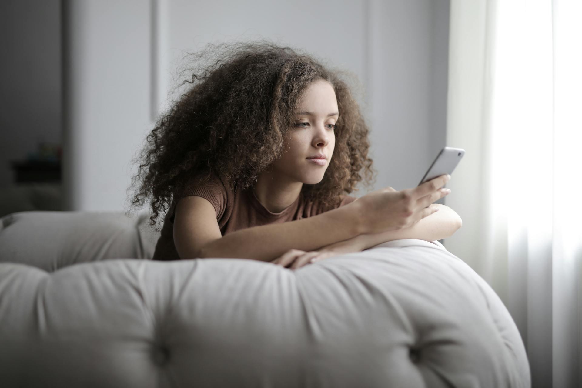 Mujer en el sillón tomando el celular.