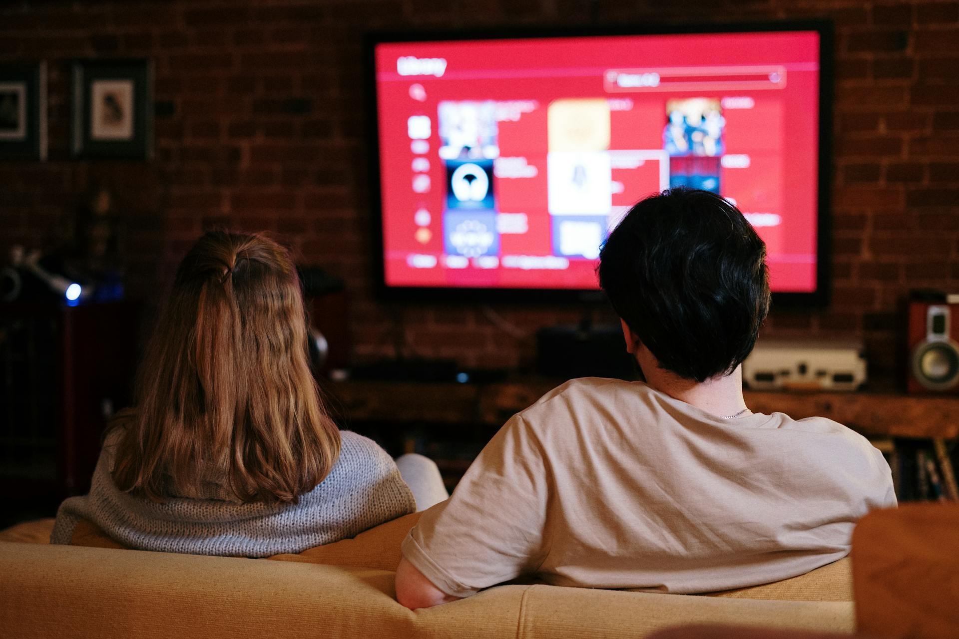 Dos personas sentadas en el sillón mirando la tv. 