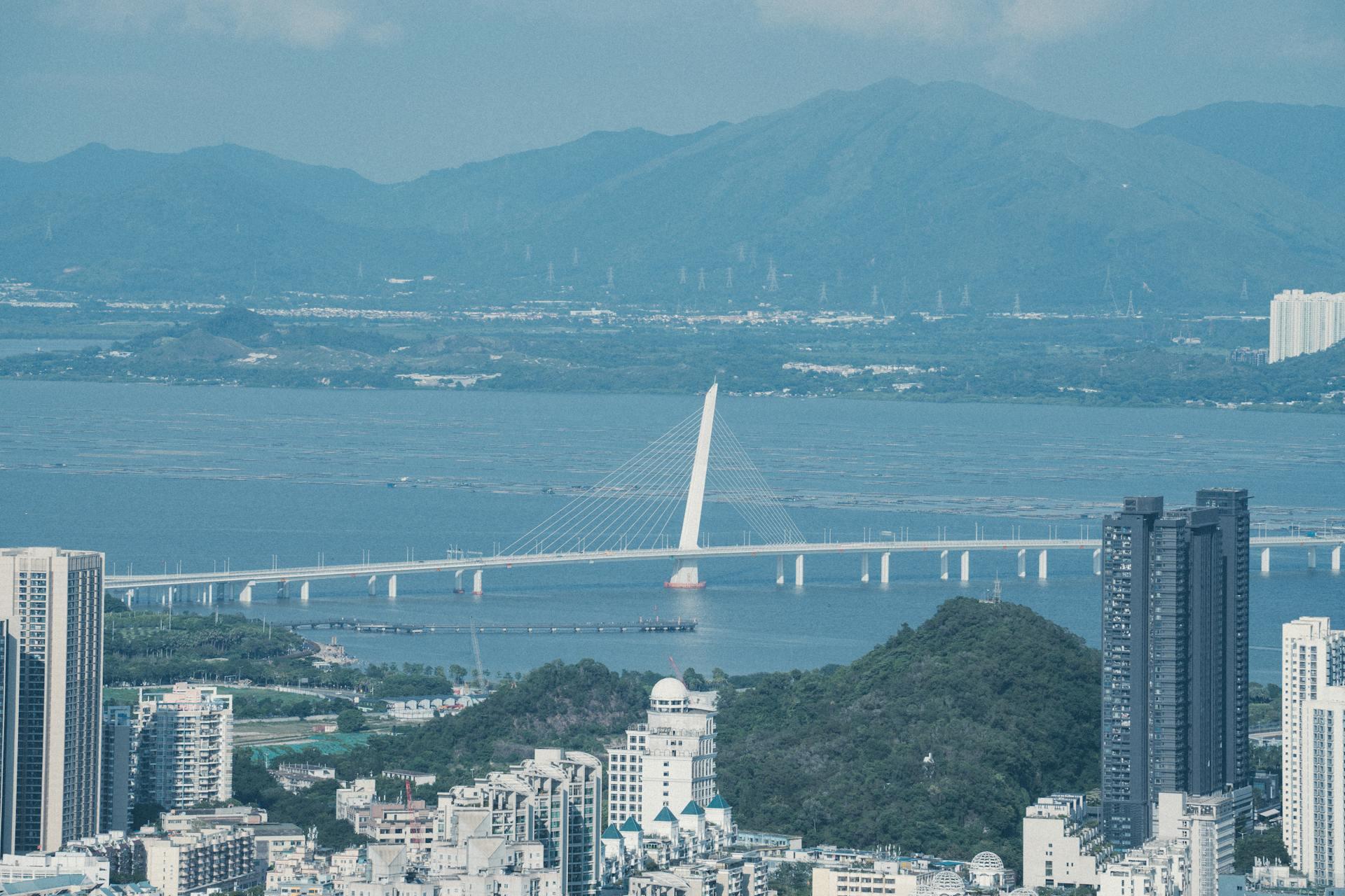 Ciudad al lado del puente sobre el agua y fondo de montañas.