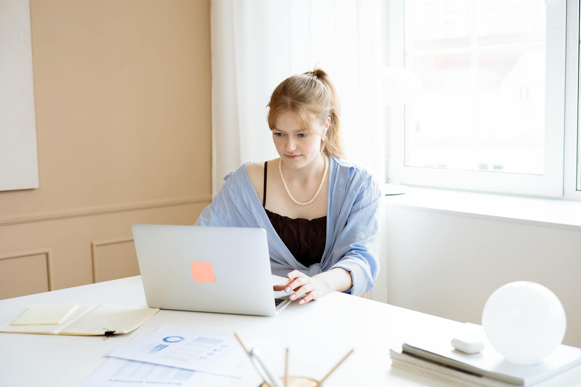 Mujer sentada en la mesa mirando la PC.