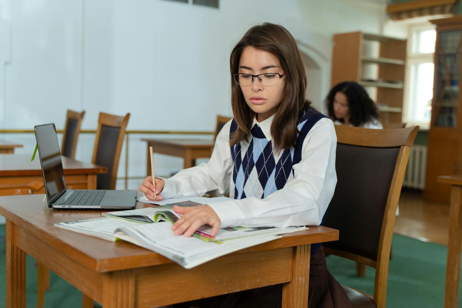 Mujer sentada en el escritorio con libros y pc.