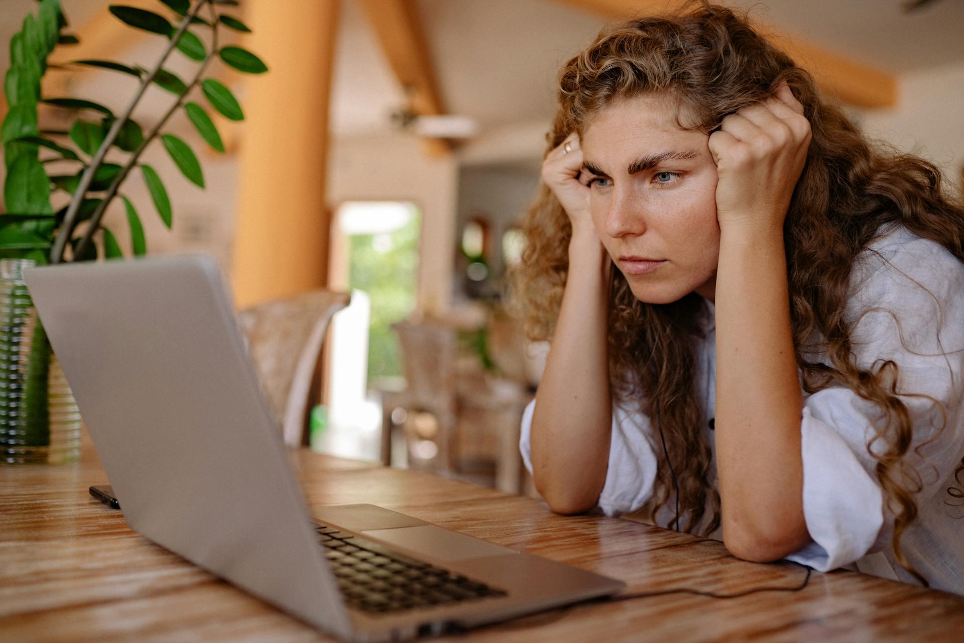 Mujer apoyada en la mesa mirando la PC. 