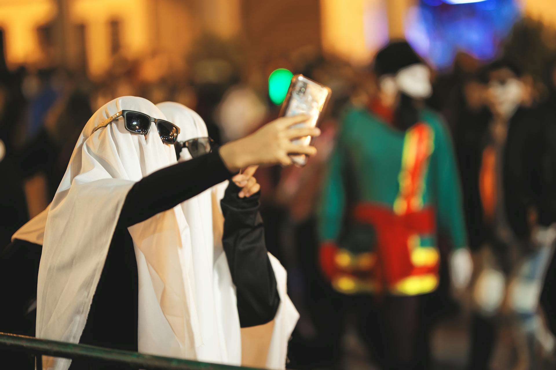 Dos personas disfrazadas de fantasma tomando una selfie.