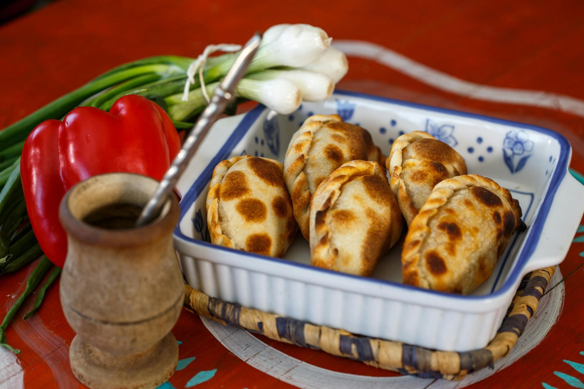 Fuente con empanadas, mate y verduras sobre la mesa.