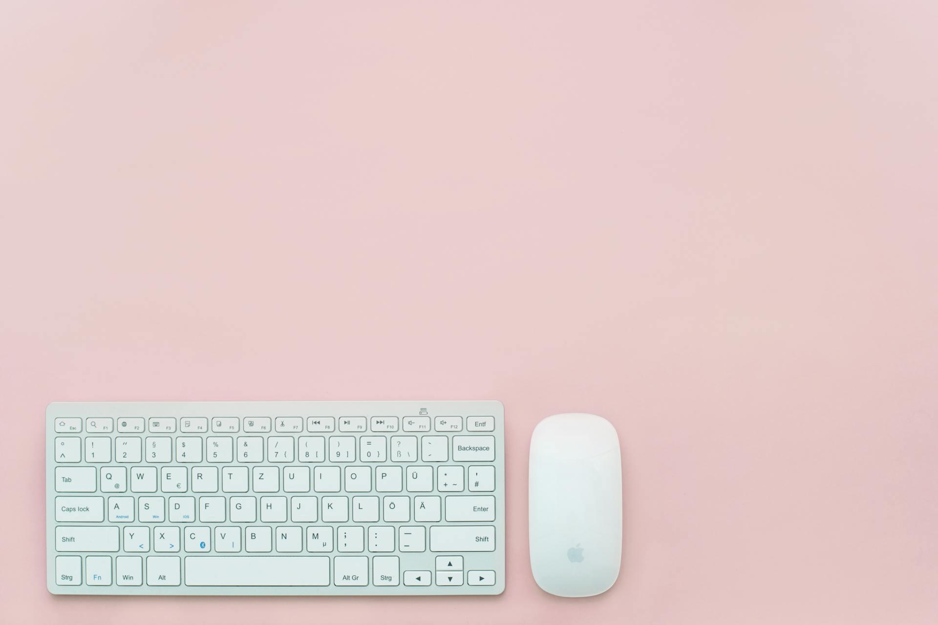 Mouse y ratón mágico de Apple sobre superficie rosa.