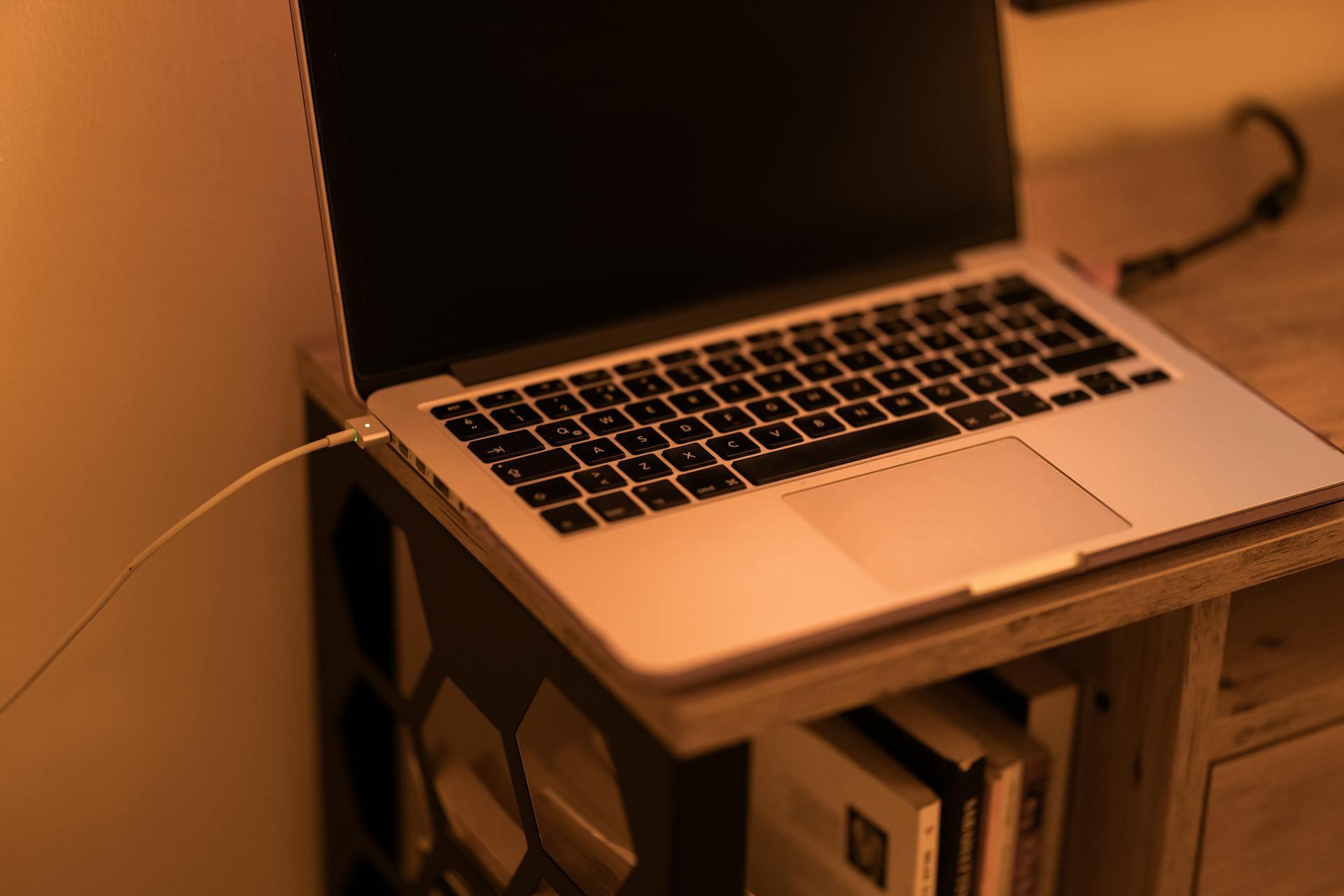 Ordenador portátil con cable sobre una mesa de madera.